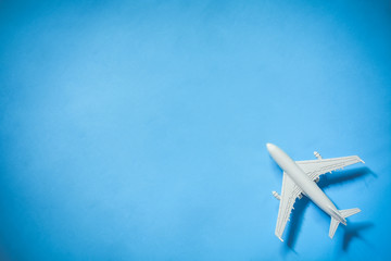 white toy airplane model over blue color background with copy space, concept of travel