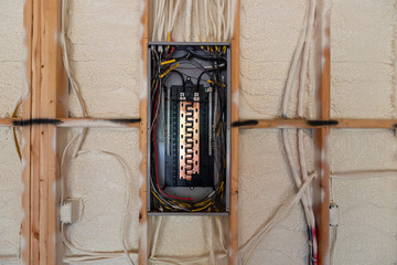 Electrical Circuit Breaker panel in new home construction, with spray foam insulation and negative space