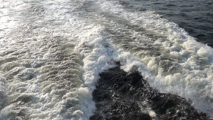 Ocean wake waves foaming up from the propellers of a ship.