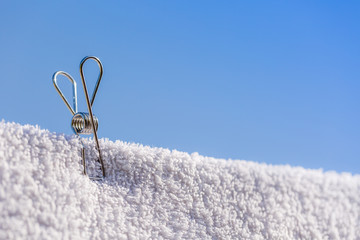 single stainless steel wire peg on a white towel with blue sky background