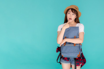 Beautiful portrait young asian woman wearing hat smiling and thinking idea with holding backpack to travel summer trip in holiday in vacation isolated blue background, tourist asia girl is having bag.