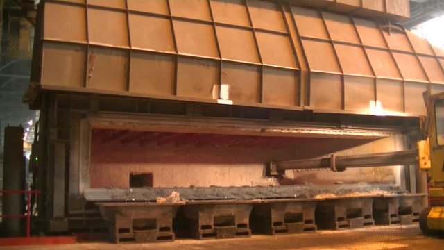 Scraping slag from molten aluminum in a furnace. Long metal manipulator.
