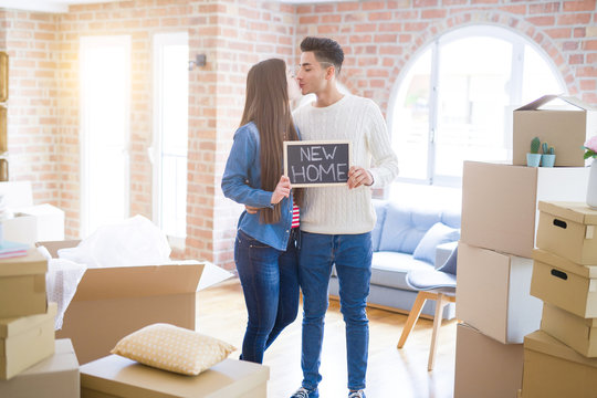 Young beautiful asian couple smiling happy holding blackboard with new home text, hugging in love moving to a new house