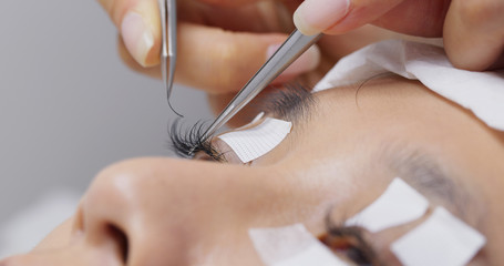 Beautician and young woman in a beauty salon with eye lash extension