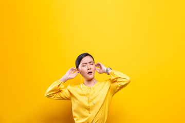Fototapeta na wymiar Woman with earphones listening music on isolated yellow background
