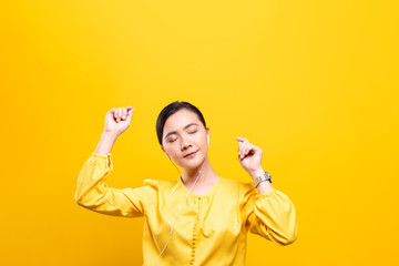 Woman with earphones listening music on isolated yellow background