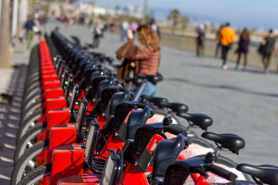 Barcelona, Spain - February 26, 2019 - Red bicycles belonging to the public transportation sharing service Bicing line the boardwalk in the Barcelonetta neighborhood