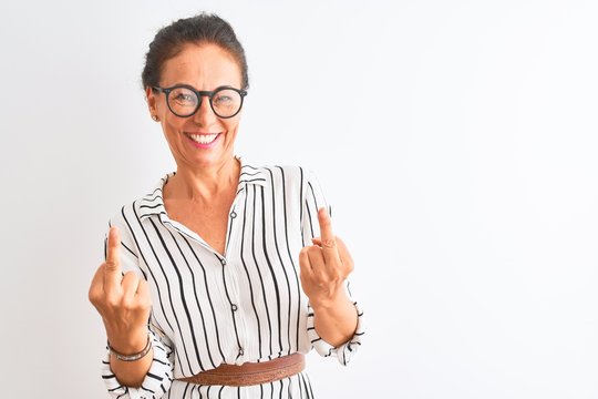 Middle age businesswoman wearing striped dress and glasses over isolated white background Showing middle finger doing fuck you bad expression, provocation and rude attitude. Screaming excited