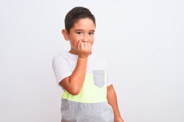 Beautiful kid boy wearing casual t-shirt standing over isolated white background looking stressed and nervous with hands on mouth biting nails. Anxiety problem.