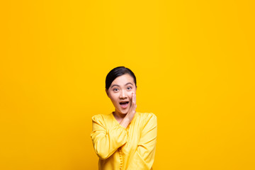Woman make gossip gesture isolated over yellow background