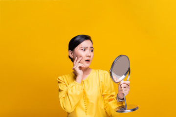 Woman looking in the mirror and worried the wrinkles on her face