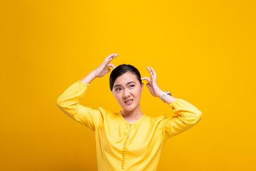 Woman scratching her head isolated over yellow background