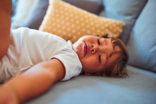 Beautiful toddler child girl wearing white bodysuit lying down on the sofa
