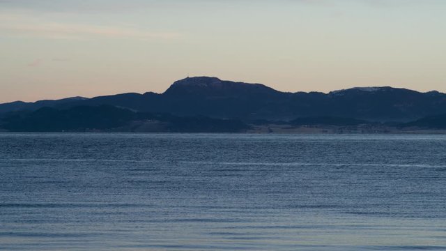 Ocean at dusk with a mountain in the back.