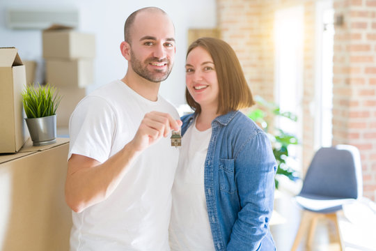 Young couple smiling very happy showing keys of new home, moving and buying new apartmet concept