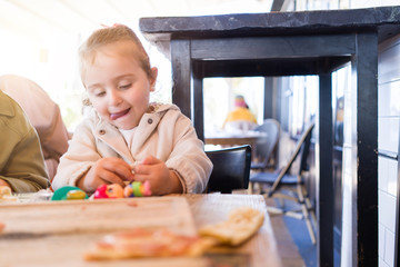 Beautiful toddler child girl sitting on baby highchair  playing with toys on the table