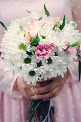 Closeup bridal bouquet of spring pink and white flowers on a blurred background, selective focus