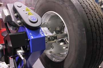 Truck wheel balance equipment, close up big vehicle tyre on balancing stand - obrazy, fototapety, plakaty
