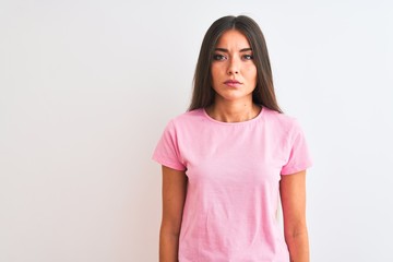 Fototapeta premium Young beautiful woman wearing pink casual t-shirt standing over isolated white background Relaxed with serious expression on face. Simple and natural looking at the camera.