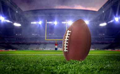 American football ball in stadium at night under spotlights