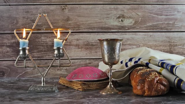 Shabbat Jewish holiday with challah bread on a candles and cup of wine.