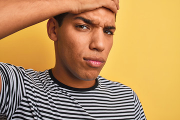 Young handsome arab man wearing navy striped t-shirt over isolated yellow background stressed with hand on head, shocked with shame and surprise face, angry and frustrated. Fear and upset for mistake.