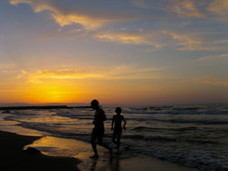 Fototapeta premium Children play at beach sunset. children playing sea beach sunset. Two boys running on the beach at the sunset time with space for text.