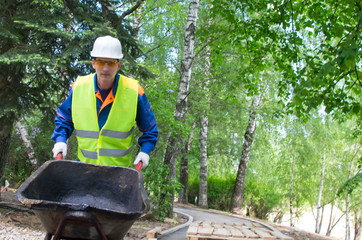 a worker in protective clothing, carrying a trolley, on the right there is a place for inscription