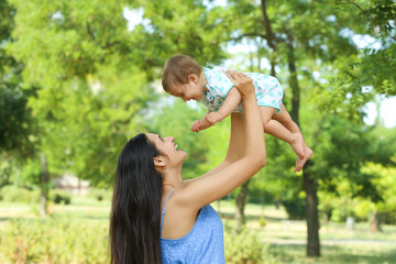 Fototapeta premium Beautiful mother with her cute baby in park on summer day