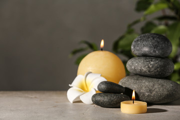 Composition with candles and spa stones on grey table. Space for text
