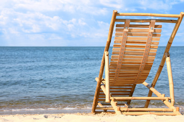 Sandy beach with empty wooden sunbed on sunny day