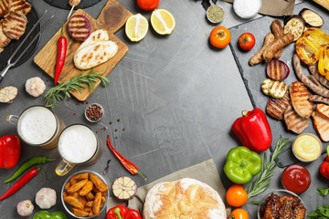 Frame of barbecued meat and vegetables on grey table, flat lay. Space for text