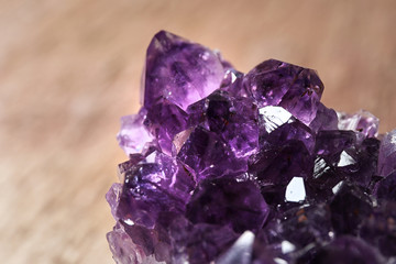 Beautiful purple amethyst gemstone on blurred brown background, closeup