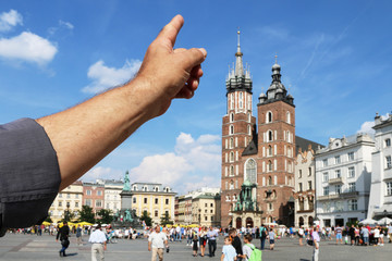 KRAKOW, POLAND - JULY 09, 2019: Tourist is pointing with his finger at the Mariacki Church