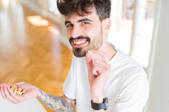 Young man eating hazelnuts, close up of hand with a bunch of healthy nuts