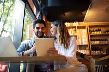 Couple have fun while looking on laptop at cafe