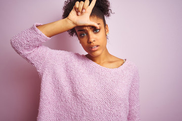 Young african american woman wearing winter sweater standing over isolated pink background making...