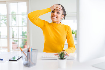 Young african american girl working using computer stressed with hand on head, shocked with shame and surprise face, angry and frustrated. Fear and upset for mistake.