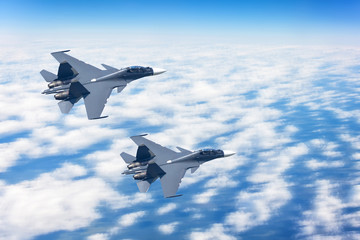 Fototapeta na wymiar Two fighters jet in the sky at high speed flying a combat mission against the background of clouds.