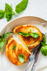 Fried sandwiches with cheese and basil on white plate.