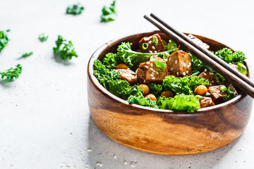 Teriyaki tofu salad with kale and chickpeas in a wooden bowl, copy space.