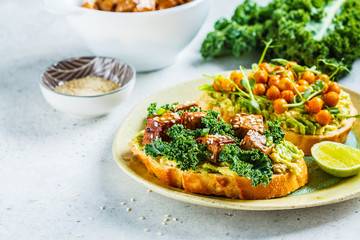 Vegan open sandwiches with guacamole, tofu, chickpeas and sprouts on a plate.