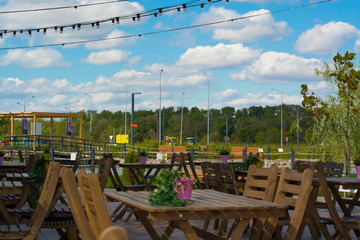 Outdoor cafe. Wooden tables and chairs. Garlands. Summer beautiful background. Beautiful design.