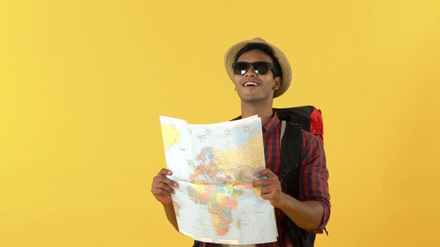 Smiling Asian male backpacker walking and looking at the map