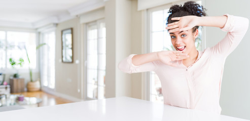 Wide angle of beautiful african american woman with afro hair Smiling cheerful playing peek a boo with hands showing face. Surprised and exited