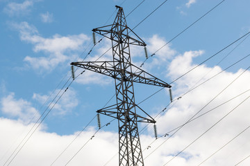 High-voltage technological power lines on metal poles with powerful power wires against the sky