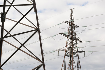 High-voltage technological power lines on metal poles with powerful power wires against the sky