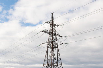 High-voltage technological power lines on metal poles with powerful power wires against the sky