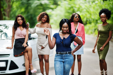 Fototapeta na wymiar Group of five happy african american girls posed against car, one of them show keys.