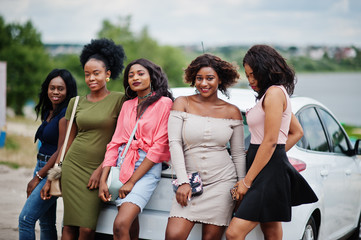 Group of five happy african american girls posed against car.